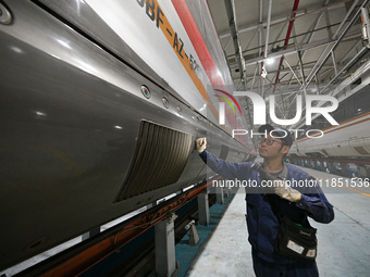 A ground service mechanic inspects a bullet train at the maintenance garage of the Nanjing South Bullet Train service station in Nanjing, Ji...