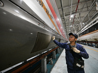 A ground service mechanic inspects a bullet train at the maintenance garage of the Nanjing South Bullet Train service station in Nanjing, Ji...