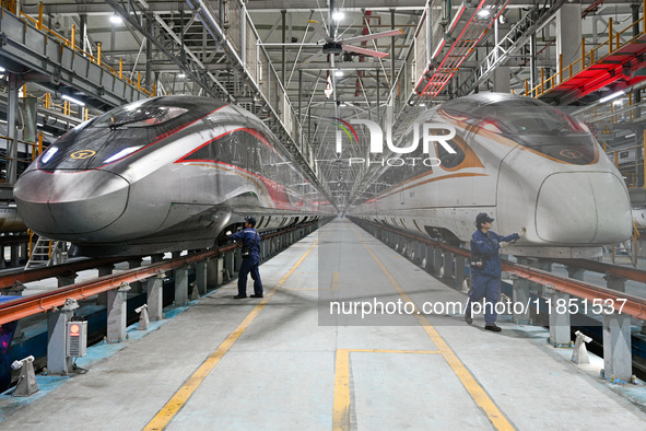 A ground service mechanic inspects a bullet train at the maintenance garage of the Nanjing South Bullet Train service station in Nanjing, Ji...