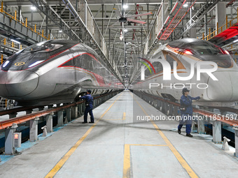 A ground service mechanic inspects a bullet train at the maintenance garage of the Nanjing South Bullet Train service station in Nanjing, Ji...