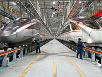 A ground service mechanic inspects a bullet train at the maintenance garage of the Nanjing South Bullet Train service station in Nanjing, Ji...