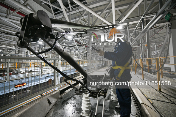 A ground service mechanic inspects a bullet train at the maintenance garage of the Nanjing South Bullet Train service station in Nanjing, Ji...