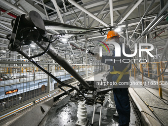 A ground service mechanic inspects a bullet train at the maintenance garage of the Nanjing South Bullet Train service station in Nanjing, Ji...