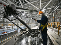 A ground service mechanic inspects a bullet train at the maintenance garage of the Nanjing South Bullet Train service station in Nanjing, Ji...