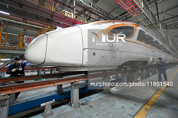 A ground service mechanic inspects a bullet train at the maintenance garage of the Nanjing South Bullet Train service station in Nanjing, Ji...