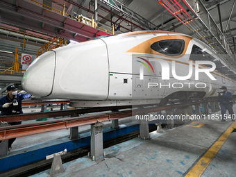 A ground service mechanic inspects a bullet train at the maintenance garage of the Nanjing South Bullet Train service station in Nanjing, Ji...