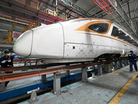 A ground service mechanic inspects a bullet train at the maintenance garage of the Nanjing South Bullet Train service station in Nanjing, Ji...