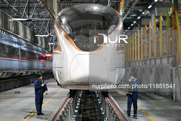 A ground service mechanic inspects a bullet train at the maintenance garage of the Nanjing South Bullet Train service station in Nanjing, Ji...