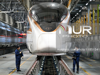 A ground service mechanic inspects a bullet train at the maintenance garage of the Nanjing South Bullet Train service station in Nanjing, Ji...