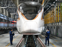 A ground service mechanic inspects a bullet train at the maintenance garage of the Nanjing South Bullet Train service station in Nanjing, Ji...