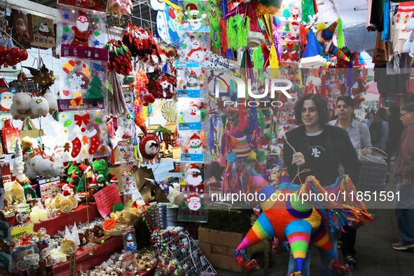 A woman carries a pinata through a market where different items are sold for the Christmas and Posadas season in the Tlalpan Center in Mexic...