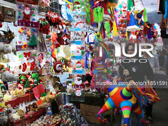 A woman carries a pinata through a market where different items are sold for the Christmas and Posadas season in the Tlalpan Center in Mexic...