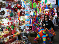 A woman carries a pinata through a market where different items are sold for the Christmas and Posadas season in the Tlalpan Center in Mexic...