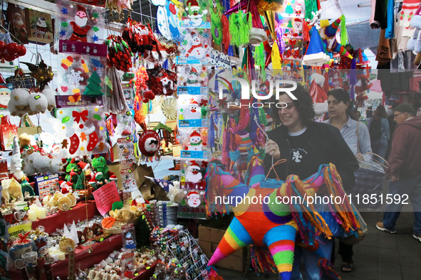 A woman carries a pinata through a market where different items are sold for the Christmas and Posadas season in the Tlalpan Center in Mexic...