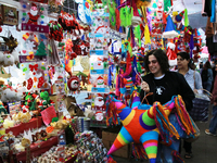 A woman carries a pinata through a market where different items are sold for the Christmas and Posadas season in the Tlalpan Center in Mexic...