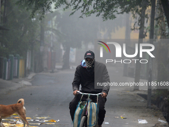 A newspaper delivery man delivers newspapers to houses on a cold and foggy day in Siliguri, India, on December 10, 2024. (