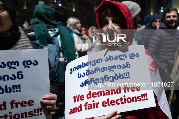 An anti-government demonstrator holds a placard reading ''We demand free and fair elections!!!'' during a protest in front of the parliament...