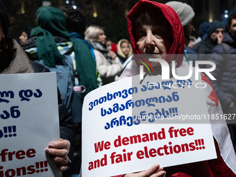 An anti-government demonstrator holds a placard reading ''We demand free and fair elections!!!'' during a protest in front of the parliament...