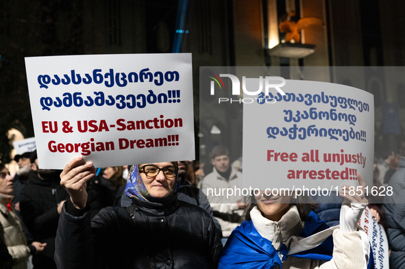 Anti-government demonstrators hold a placard reading ''We demand free and fair elections!!!'' and ''EU & USA Sanction Georgian dream!!!'' du...