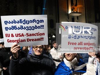 Anti-government demonstrators hold a placard reading ''We demand free and fair elections!!!'' and ''EU & USA Sanction Georgian dream!!!'' du...