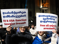 Anti-government demonstrators hold a placard reading ''We demand free and fair elections!!!'' and ''EU & USA Sanction Georgian dream!!!'' du...