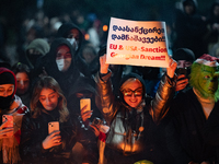 An anti-government demonstrator holds a placard reading ''EU & USA Sanction Georgian dream !!!'' during a protest in front of the parliament...