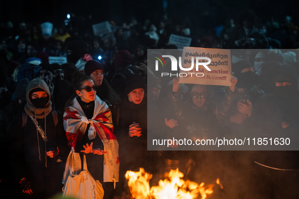 An anti-government demonstrator holds a placard reading ''EU & USA Sanction Georgian dream !!!'' during a protest in front of the parliament...