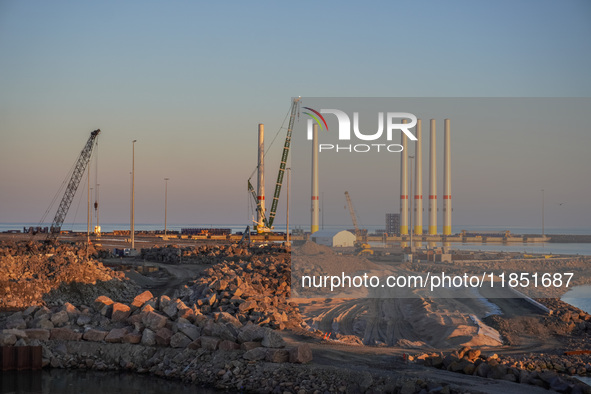 A general view of the port during sunset is seen in Ronne, Bornholm Island, Denmark, on August 6, 2024. Giant wind turbine bases are visible...