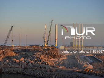 A general view of the port during sunset is seen in Ronne, Bornholm Island, Denmark, on August 6, 2024. Giant wind turbine bases are visible...