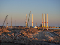 A general view of the port during sunset is seen in Ronne, Bornholm Island, Denmark, on August 6, 2024. Giant wind turbine bases are visible...