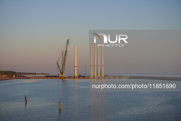 A general view of the port during sunset is seen in Ronne, Bornholm Island, Denmark, on August 6, 2024. Giant wind turbine bases are visible...