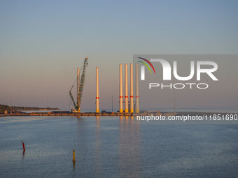 A general view of the port during sunset is seen in Ronne, Bornholm Island, Denmark, on August 6, 2024. Giant wind turbine bases are visible...