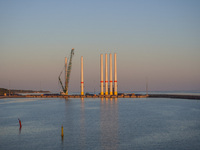 A general view of the port during sunset is seen in Ronne, Bornholm Island, Denmark, on August 6, 2024. Giant wind turbine bases are visible...