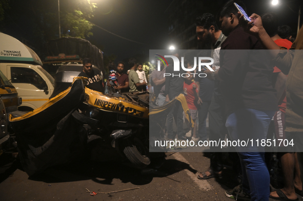 People observe a damaged auto rickshaw near an accident spot where a BEST bus loses control and crushes a few vehicles, injuring 49 people a...