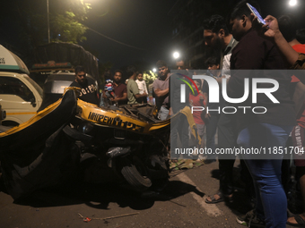 People observe a damaged auto rickshaw near an accident spot where a BEST bus loses control and crushes a few vehicles, injuring 49 people a...