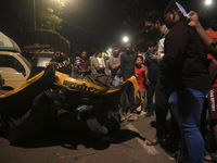 People observe a damaged auto rickshaw near an accident spot where a BEST bus loses control and crushes a few vehicles, injuring 49 people a...