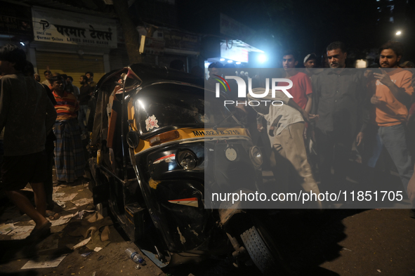 People observe a damaged auto rickshaw near an accident spot where a BEST bus loses control and crushes a few vehicles, injuring 49 people a...