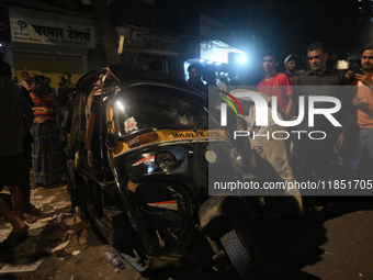 People observe a damaged auto rickshaw near an accident spot where a BEST bus loses control and crushes a few vehicles, injuring 49 people a...