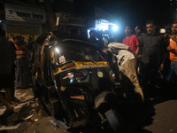 People observe a damaged auto rickshaw near an accident spot where a BEST bus loses control and crushes a few vehicles, injuring 49 people a...