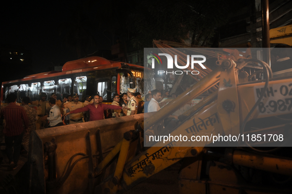 People are seen near an accident site where a BEST bus loses control and crushes a few vehicles, injuring 49 people and killing 7 people in...