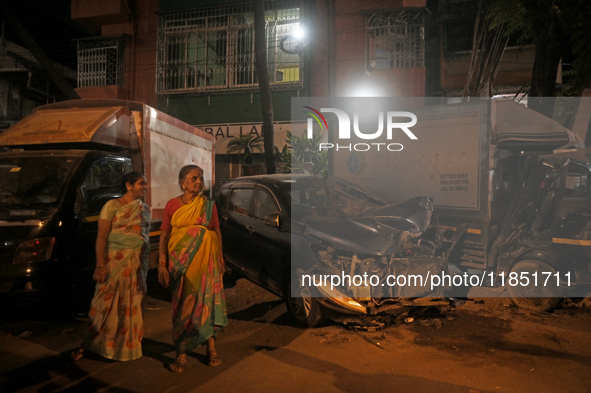 Pedestrians are near a damaged car where a BEST bus loses control and crushes a few vehicles, injuring 49 people and killing 7 people in Mum...