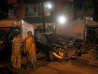 Pedestrians are near a damaged car where a BEST bus loses control and crushes a few vehicles, injuring 49 people and killing 7 people in Mum...