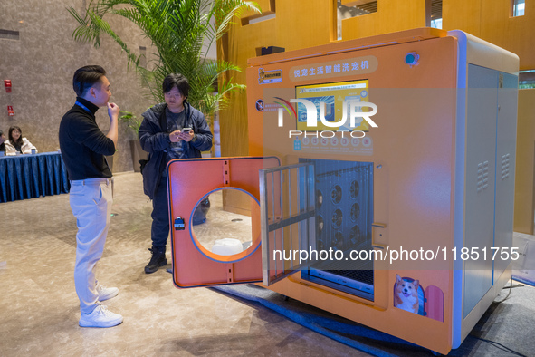 Visitors look at an automatic pet bathing pod at the 2024 Global Artificial Intelligence Product Application Expo in Suzhou, China, on Decem...