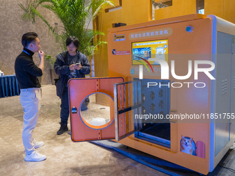 Visitors look at an automatic pet bathing pod at the 2024 Global Artificial Intelligence Product Application Expo in Suzhou, China, on Decem...