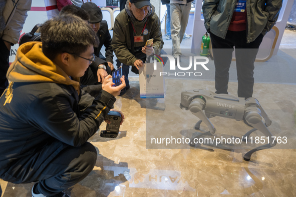 Visitors interact with a robot dog at the 2024 Global Artificial Intelligence Product Application Expo in Suzhou, China, on December 10, 202...