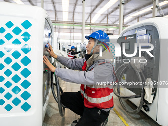 A worker debugs an intelligent mobile charging station at Nantong Guoxuan New Energy Technology Co., Ltd. in Nantong High-tech Zone, East Ch...