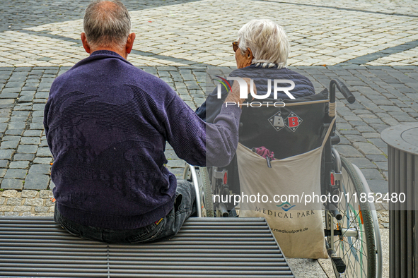 In Coburg, Germany, on September 19, 2021, an elderly man and woman share a quiet moment together in an urban square. The woman, seated in a...