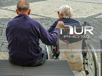 In Coburg, Germany, on September 19, 2021, an elderly man and woman share a quiet moment together in an urban square. The woman, seated in a...