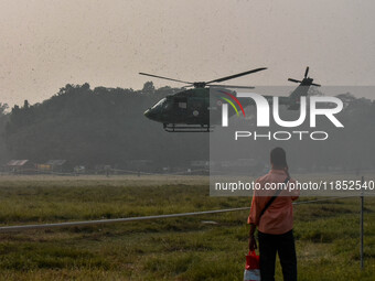 People watch Indian Army helicopters during a practice run for the upcoming Vijay Diwas celebrations in Kolkata, India, on December 10, 2024...