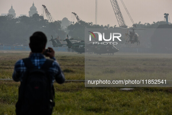 People watch Indian Army helicopters during a practice run for the upcoming Vijay Diwas celebrations in Kolkata, India, on December 10, 2024...